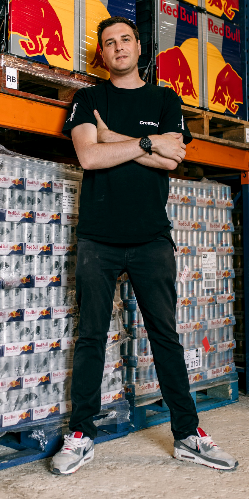 Portrait of Tom Whittle of Creation, standing in front of pallets of Red Bull.