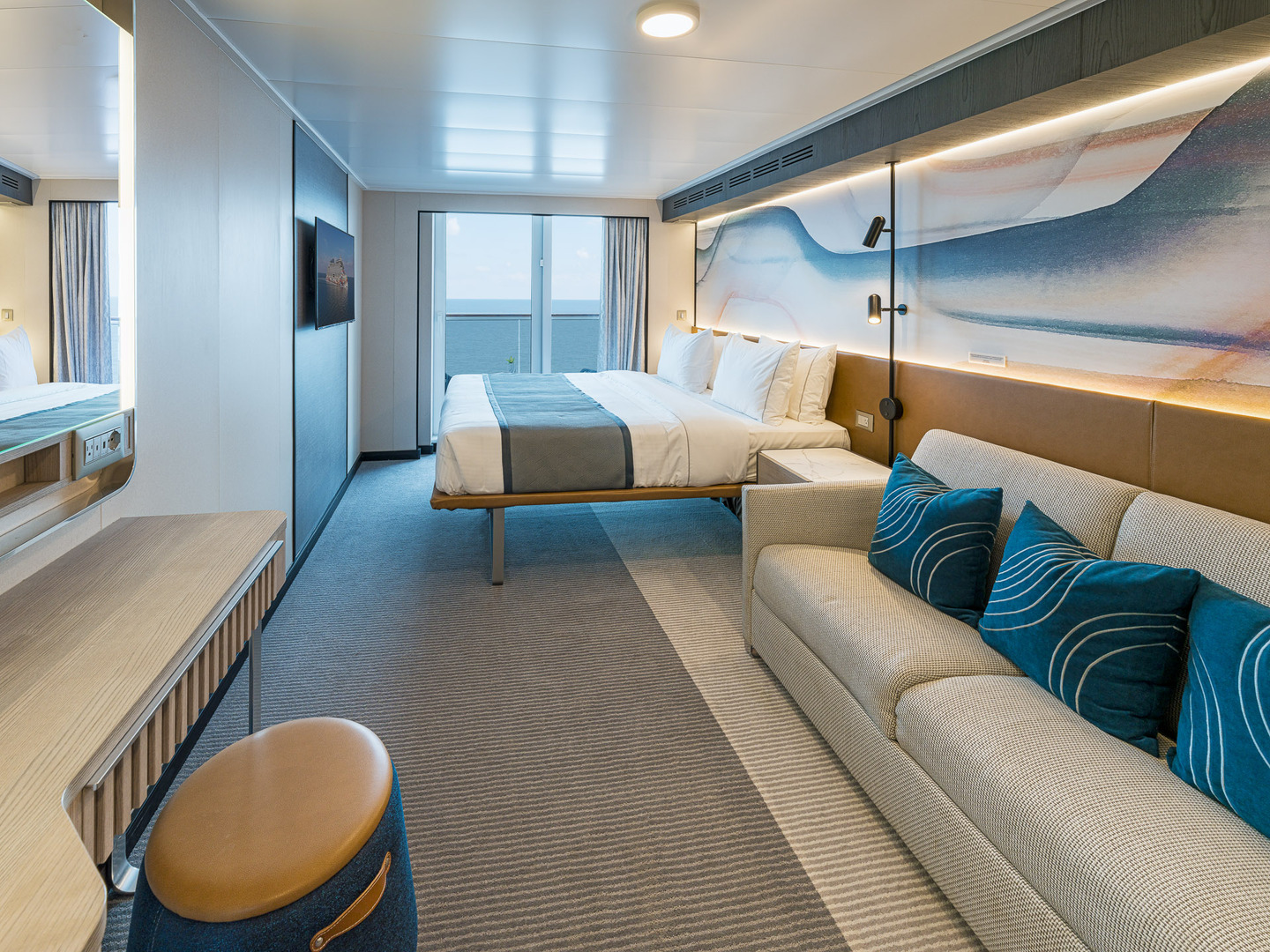 Стateroom на Norwegian Aqua с кроватью, диваном и видом на океан.