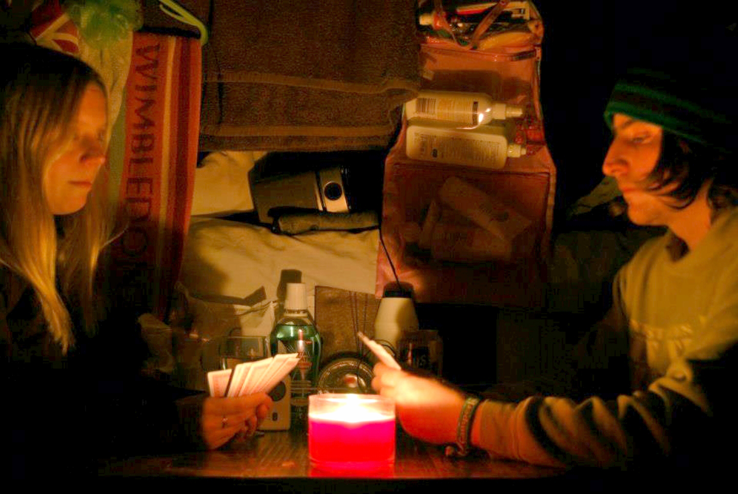 A couple playing cards by candlelight in a converted ambulance.