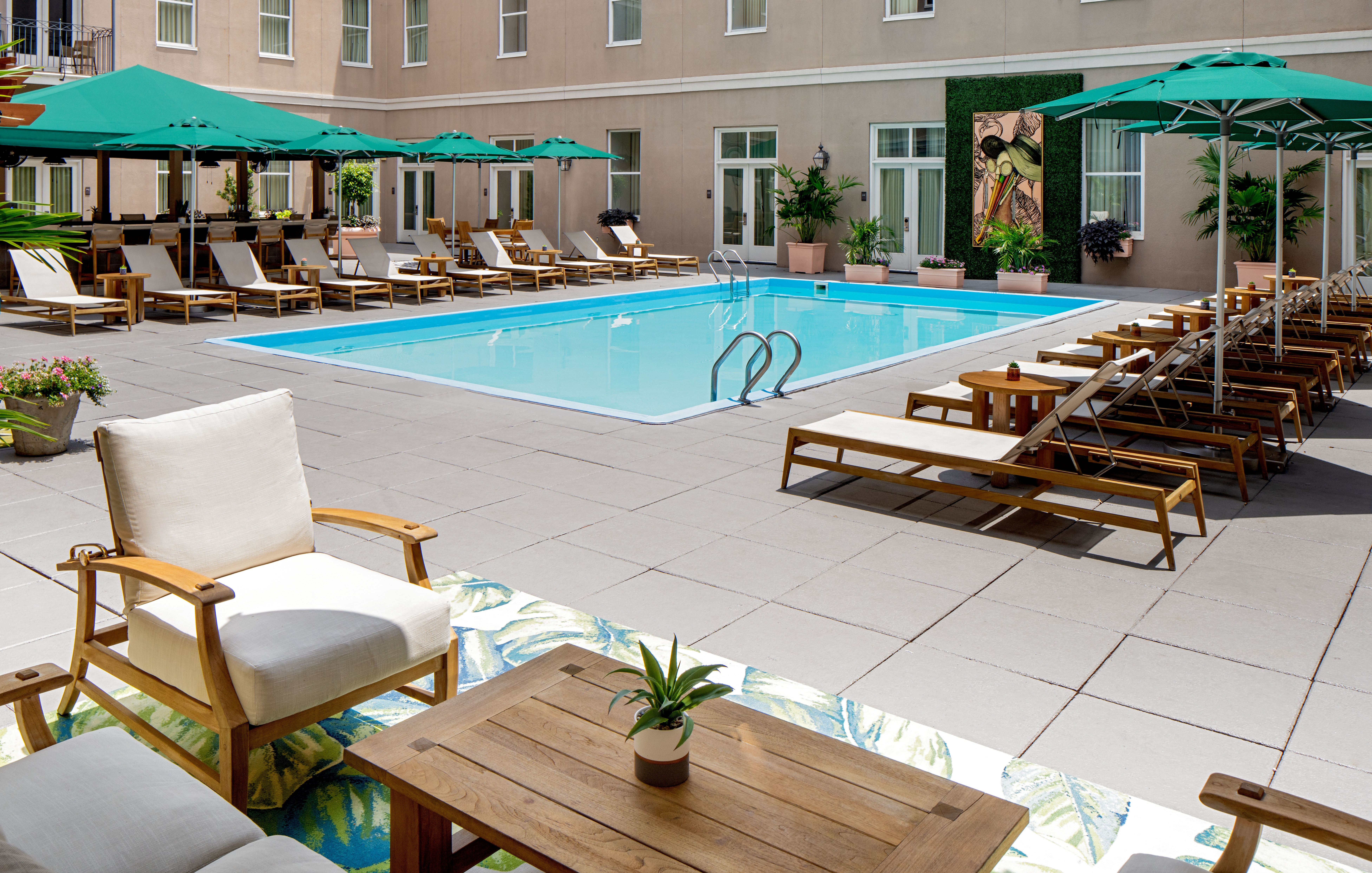 Площадка у бассейна Hyatt Centric French Quarter с шезлонгами и зонтами.