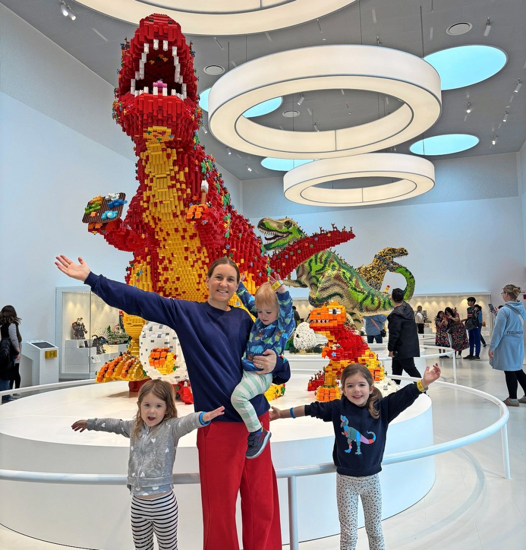 Семья позирует с большими Lego динозаврами в Lego House.