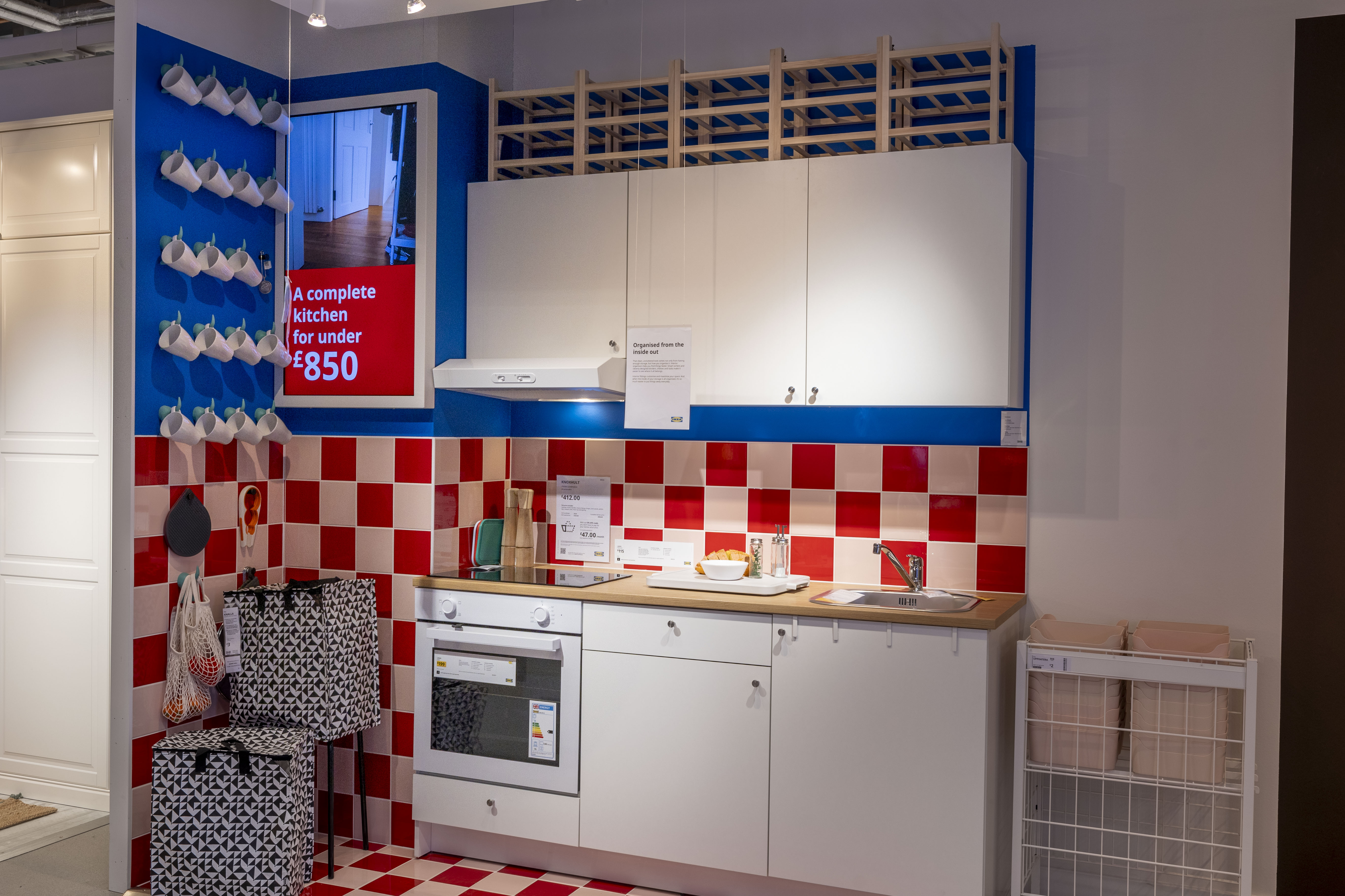 Кухонная выставка IKEA с красной и белой клетчатой плиткой на стене.