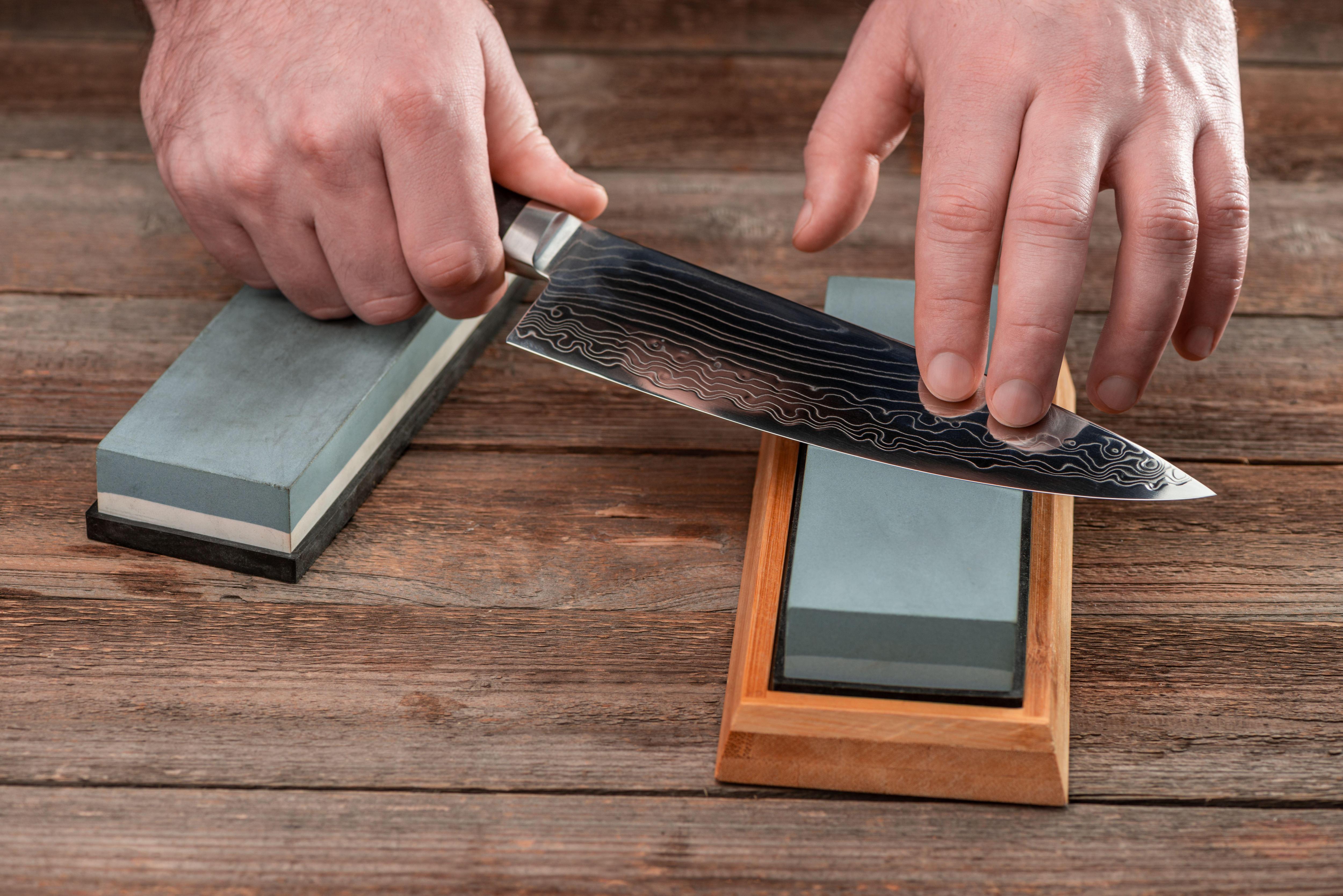 Person sharpening a Japanese knife on a whetstone.