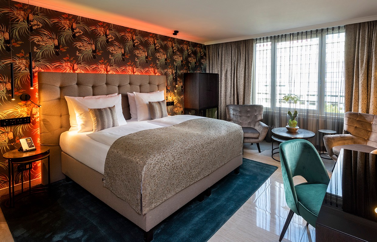 Номер в отеле Palace Berlin с большой кроватью, зоной для сидения и рабочим столом.