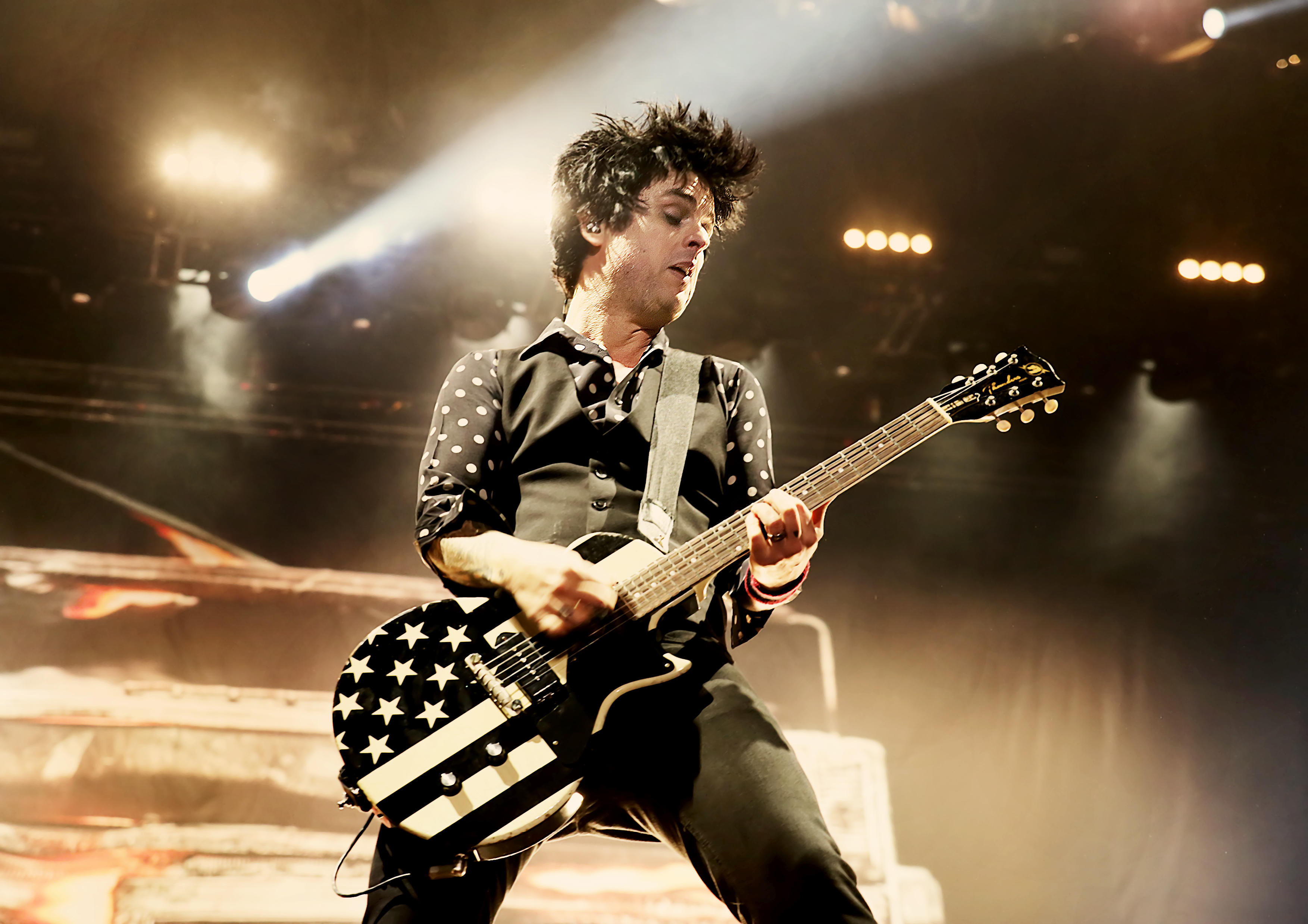 Билли Джо Армстронг из Green Day играет на гитаре на сцене.