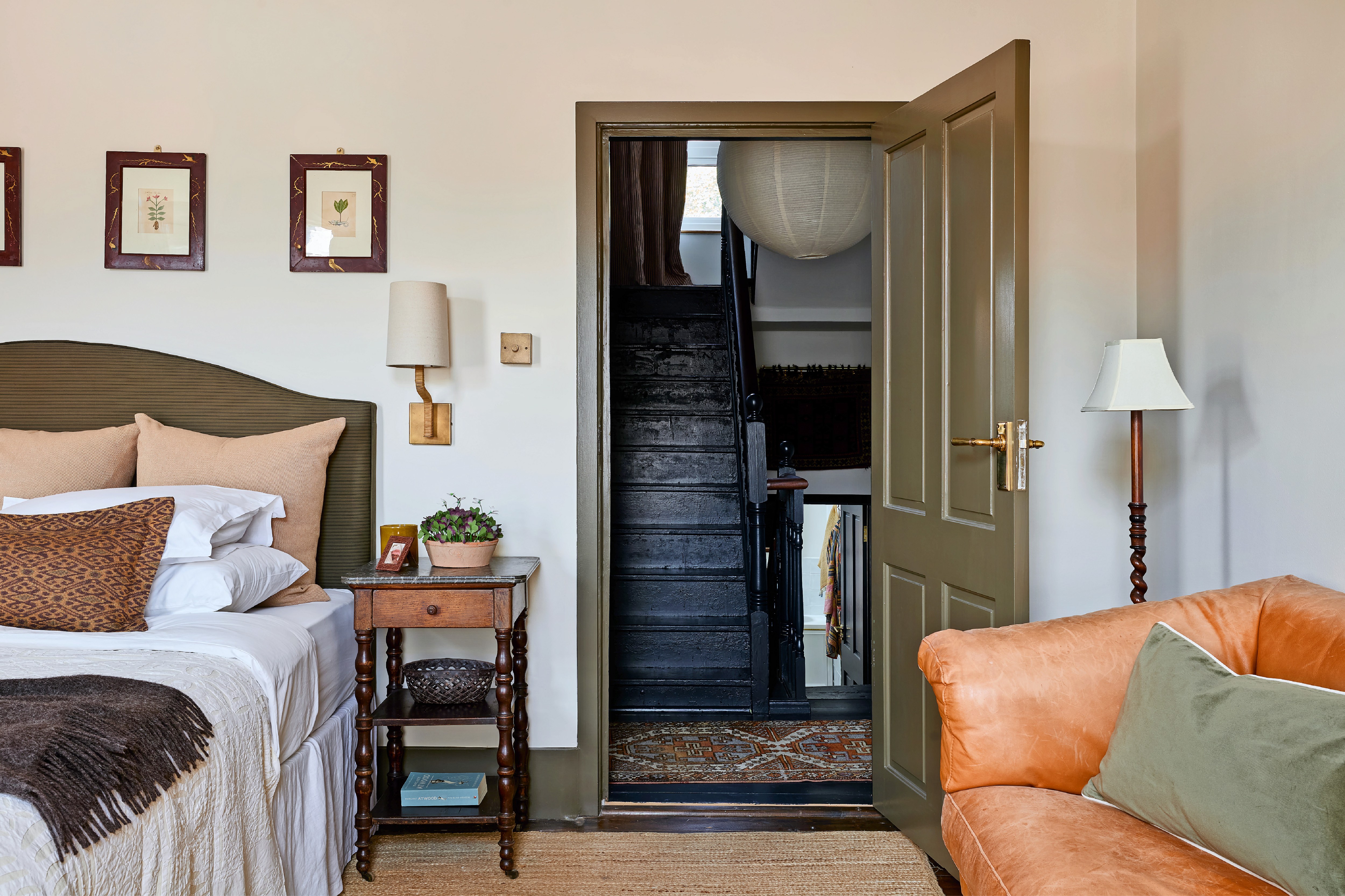 Bedroom with a view of a dark staircase through an open doorway.