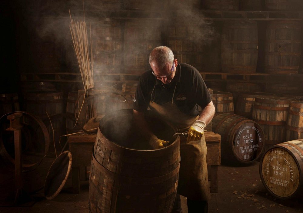 A worker at the Glenfiddich distillery tending to a whisky barrel.