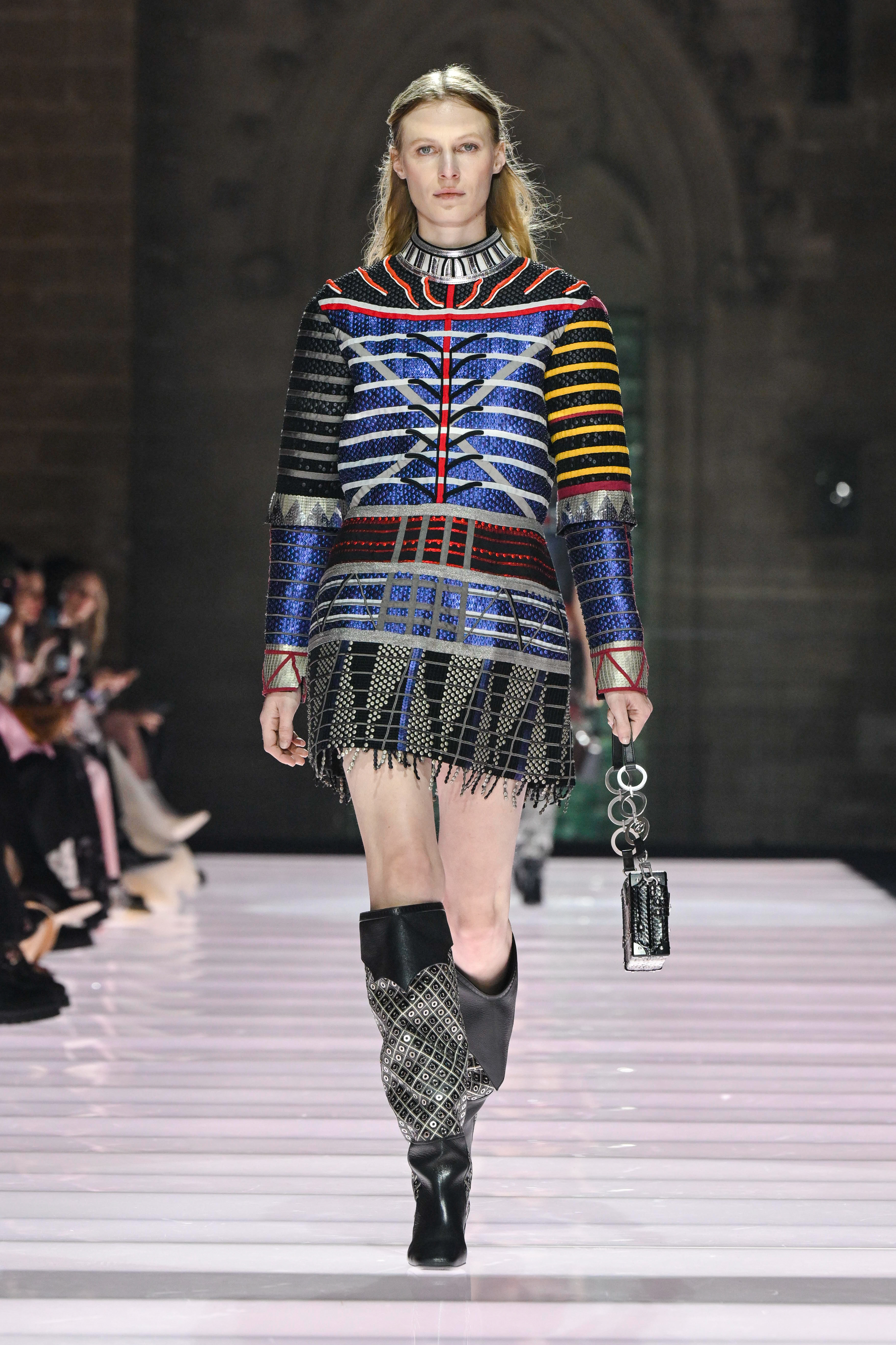 Модель на показе Louis Vuitton Cruise 2026 в мини-платье с рисунком и ботинках.