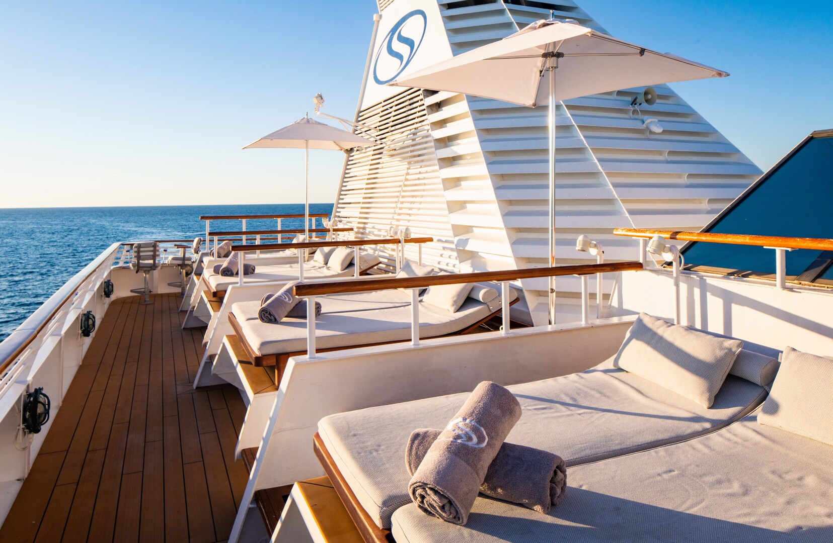 Солнечная палуба SeaDream Yacht Club с lounge chairs и зонтами.