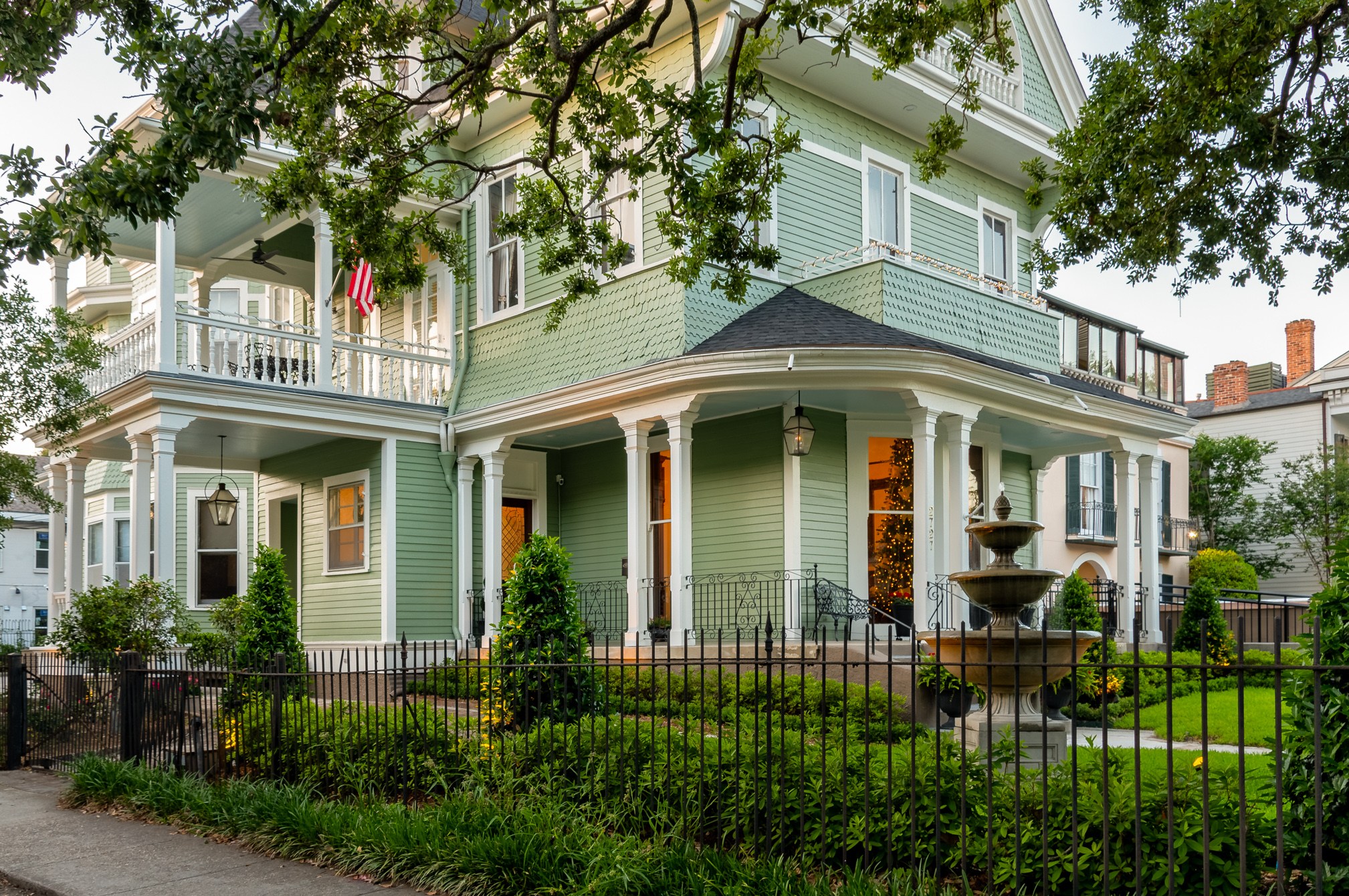 Grand Victorian дом с фонтаном и рождественской елкой, видимыми через окно.