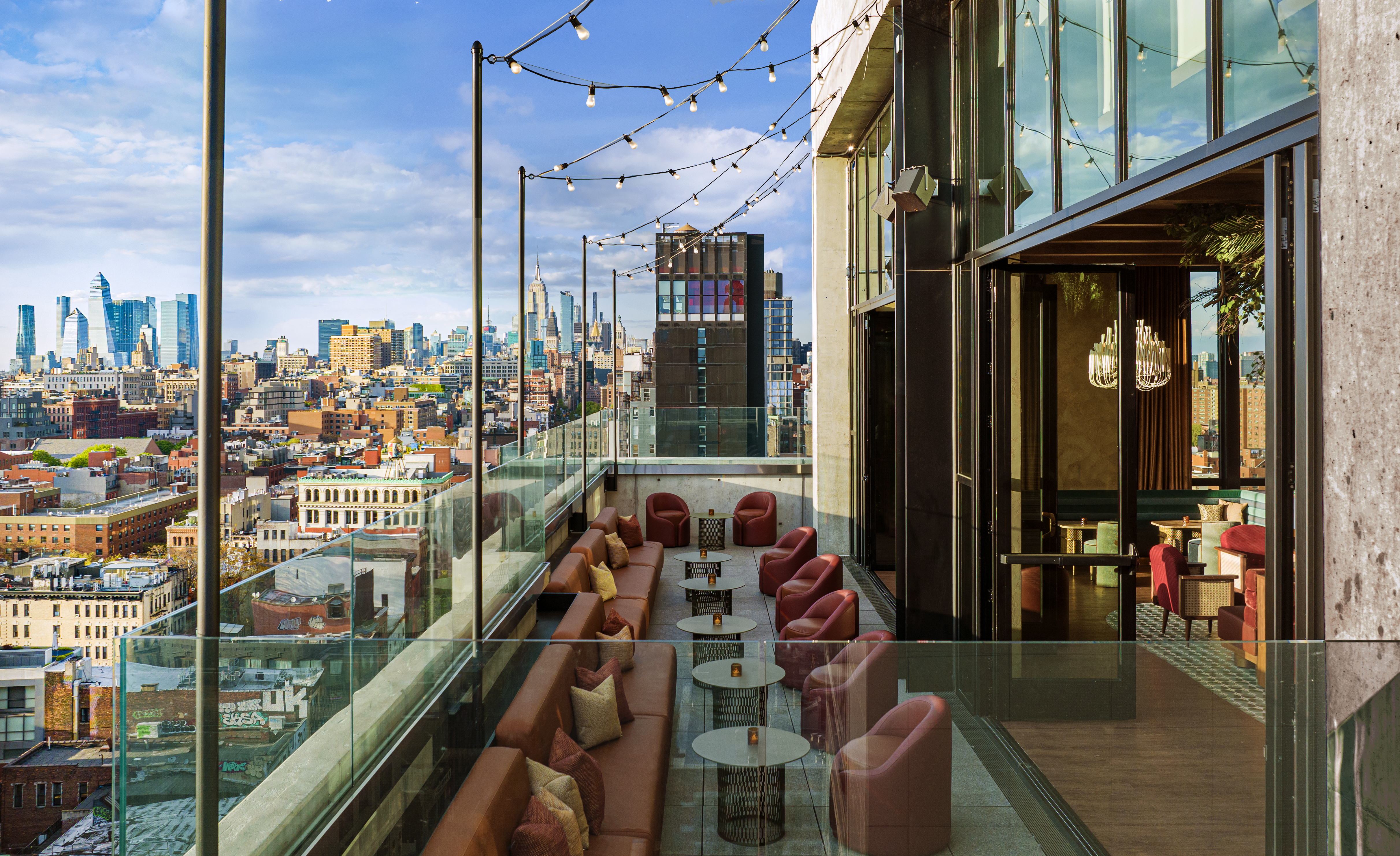 Терраса с столиками и видами на город в Moxy NYC Lower East Side - один из лучших отелей в Нью-Йорке