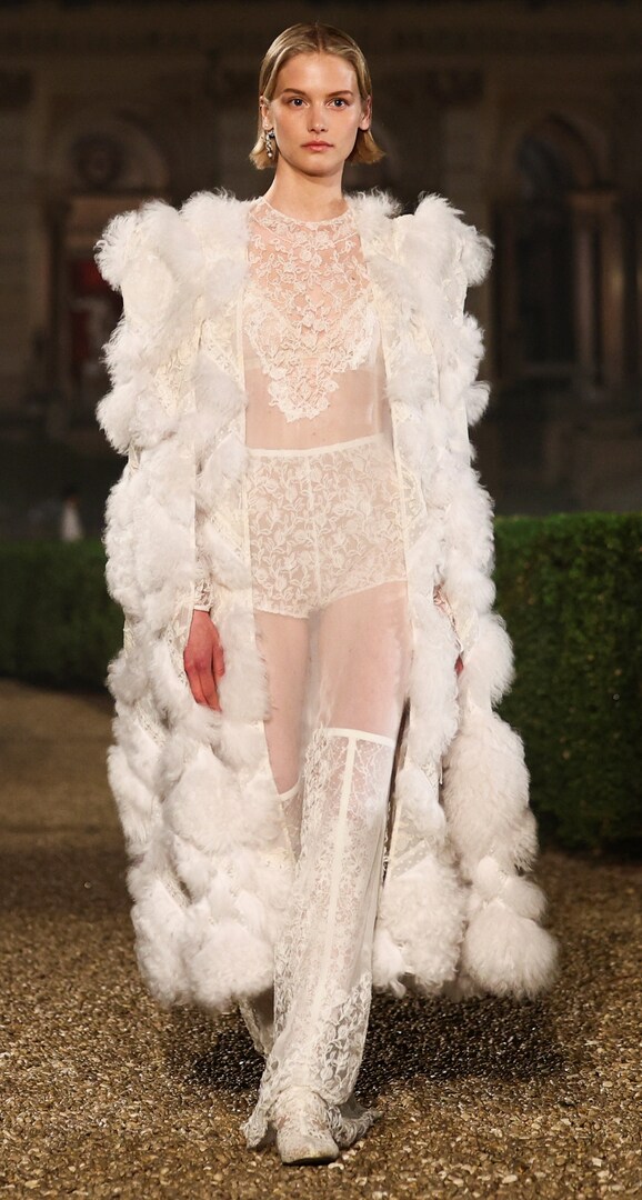 Модель демонстрирует белый кружевной наряд на показе Christian Dior Cruise 2026.