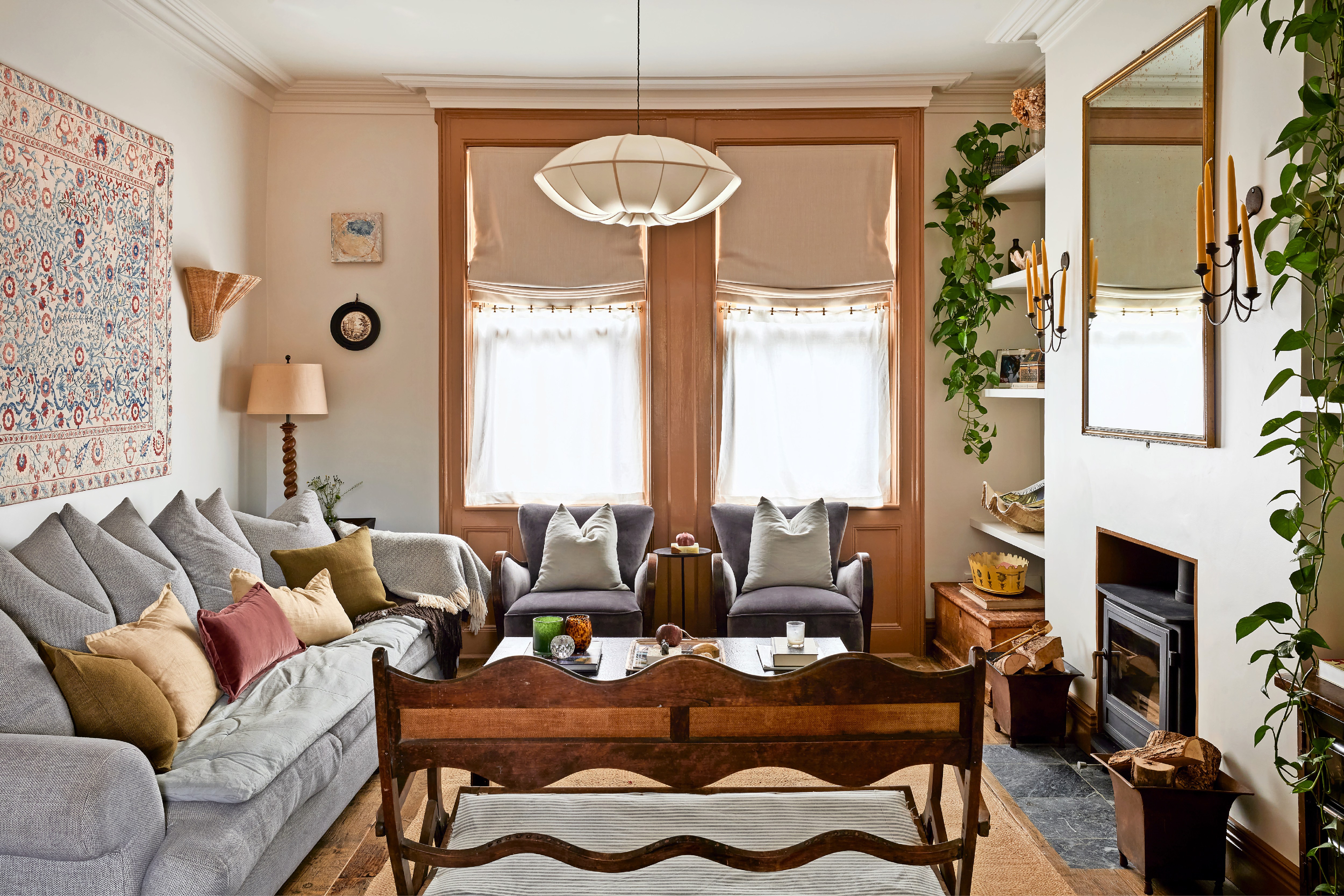 Living room with gray sofa, armchairs, and wood-burning stove.